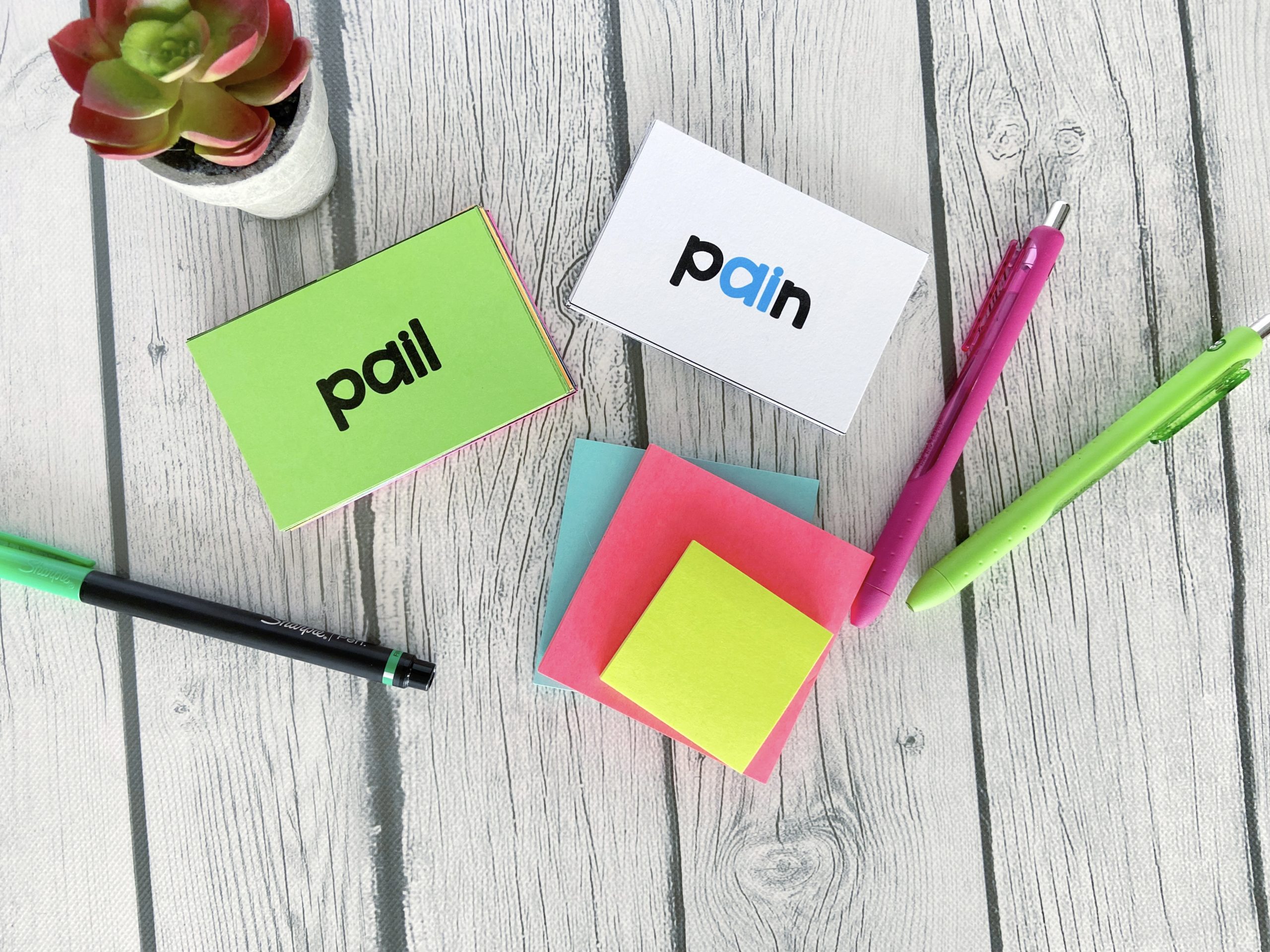 long vowel flashcards The words "pail" and "pain" on flashcards displayed with pens and sticky notes.